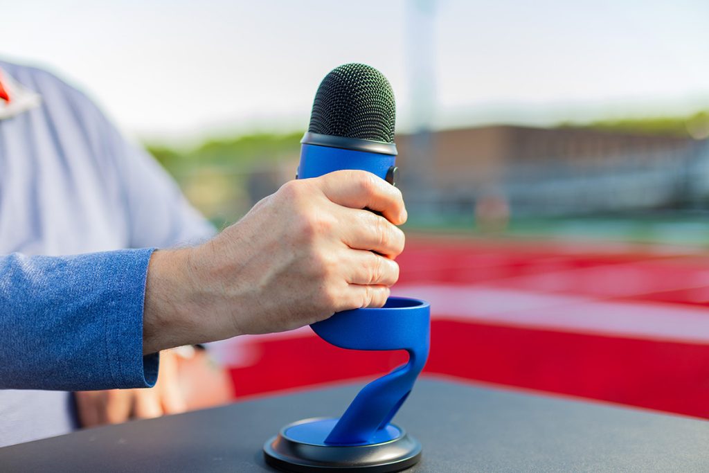 a hand wrapped around a podcast microphone